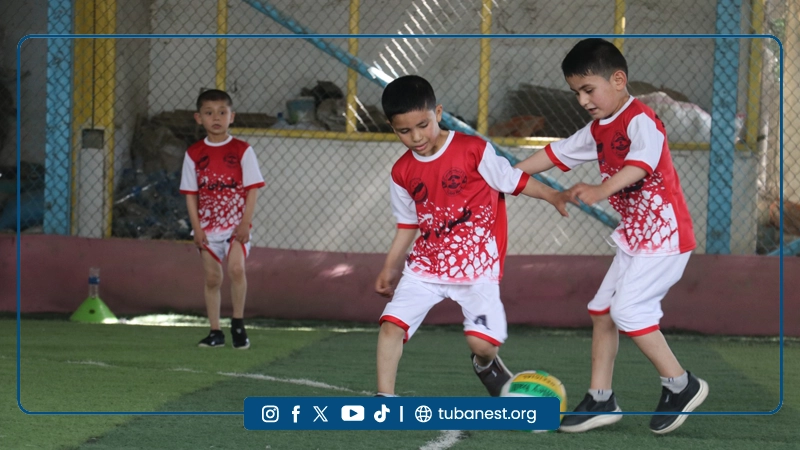 Children participating in a sports and recreational program organized by Tuba Nest in Taloqan, including football activities and a joyful Shir Yakh treat, promoting health, happiness, and child development.